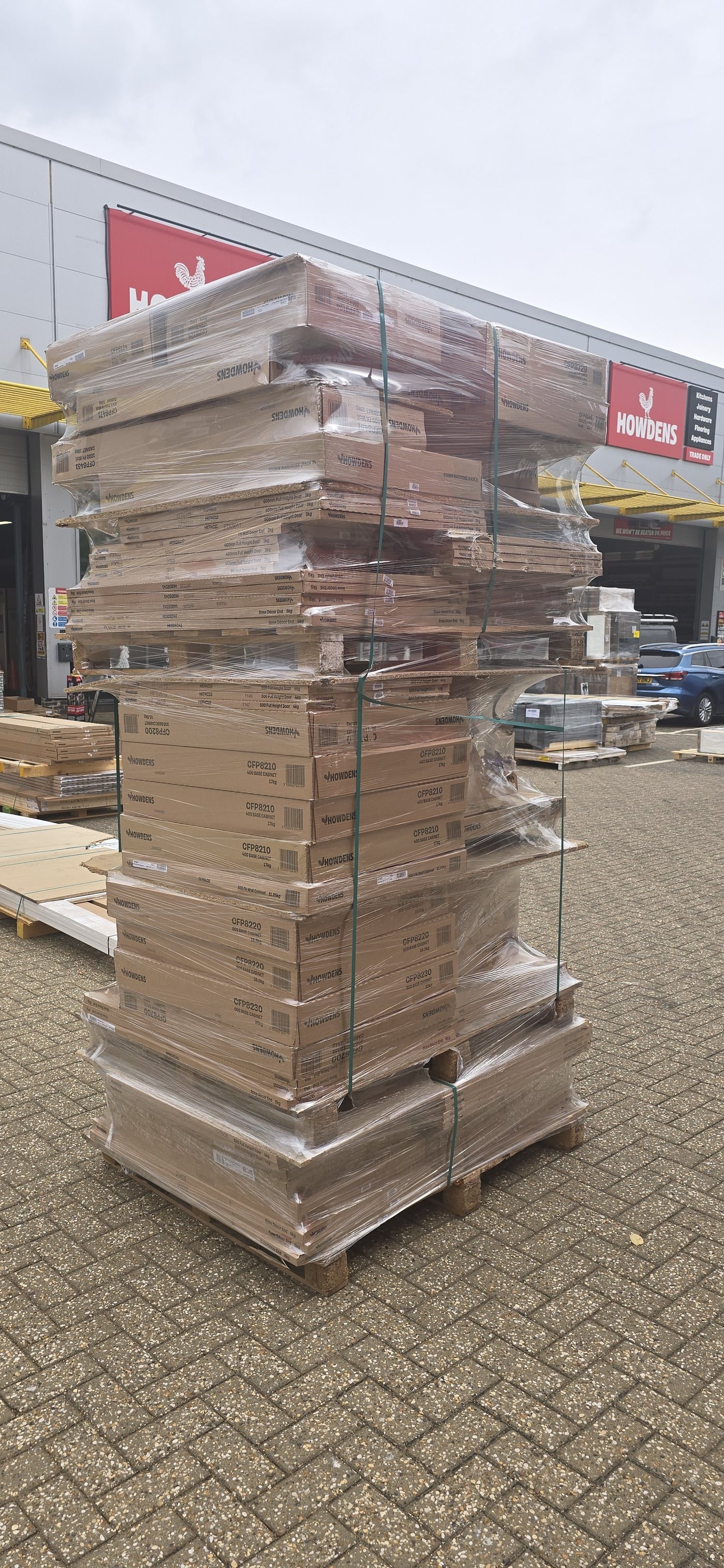 The pallet as it arrived from the factory, machine-wrapped over its own strapping — the stack leaning and the film loose across the boxes