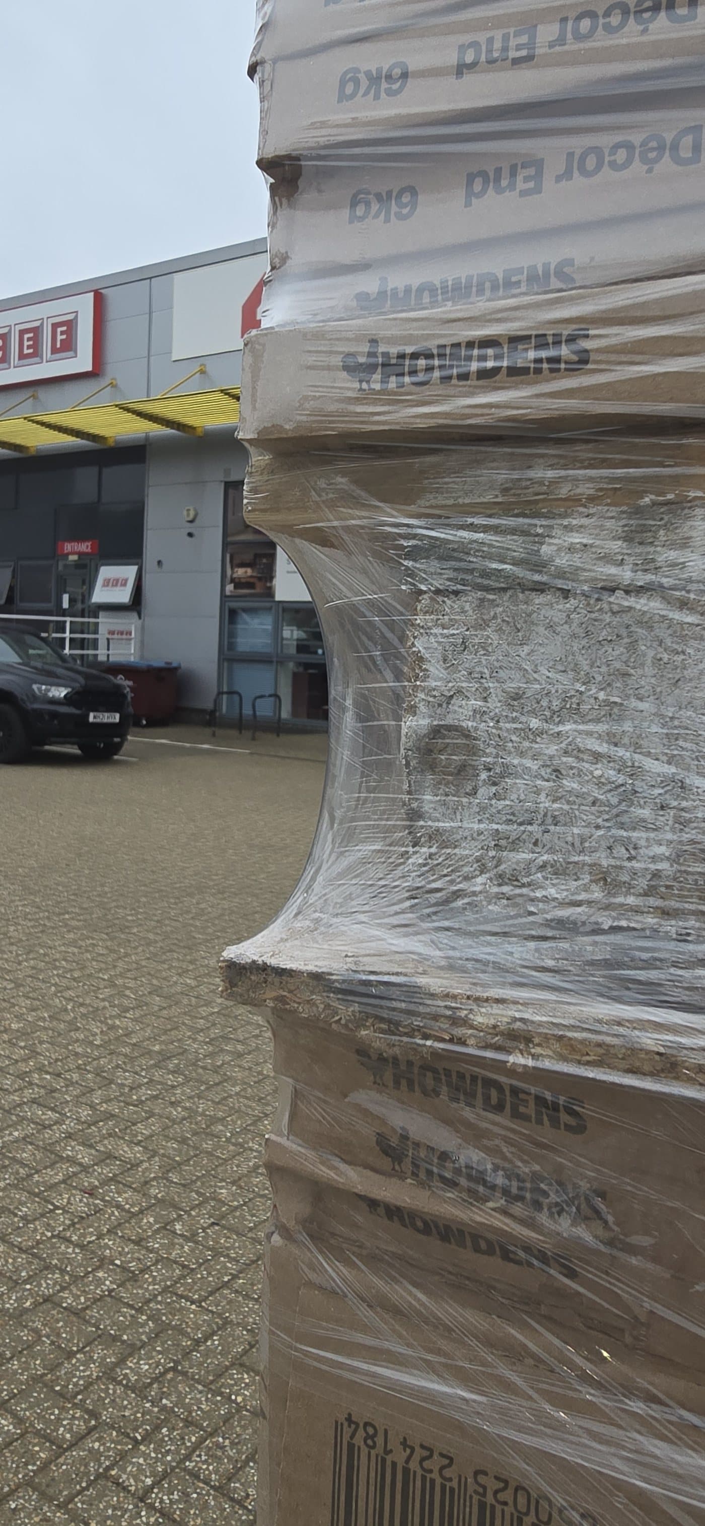 The corner of the rewrapped pallet: the film taut against sharp carton edges with no tear running into the web