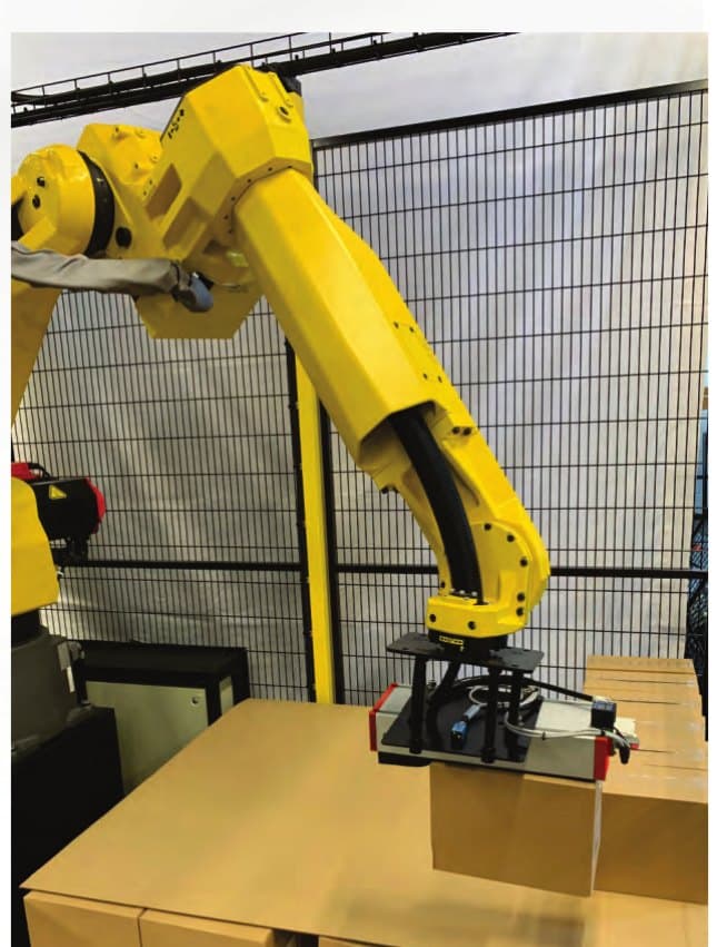 An ATS robotic palletising cell at work: the arm setting a carton onto a part-built pallet inside its guarding