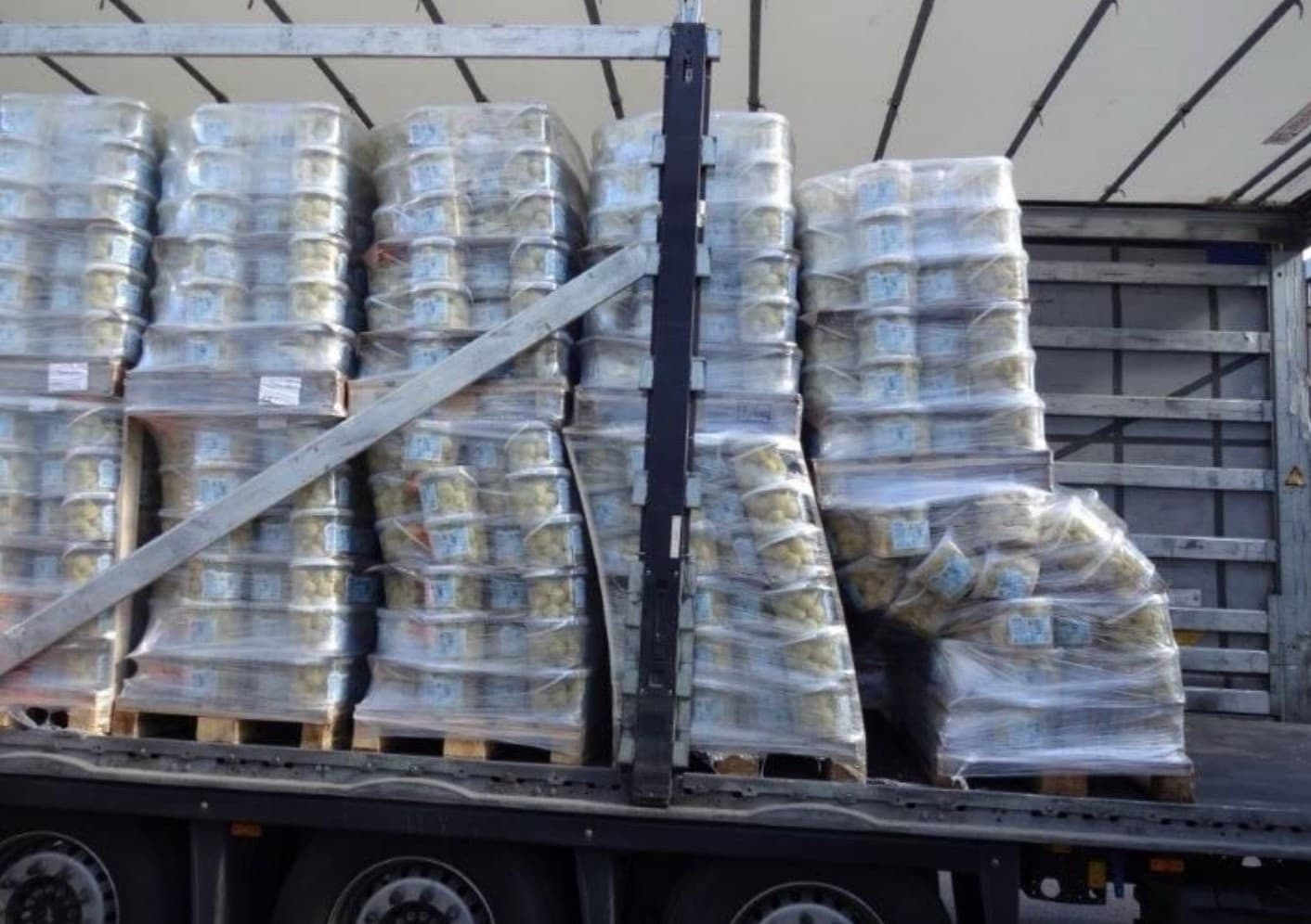 A curtainsider part-way through a delivery: four pallets of tubbed product still square, and a fifth collapsed sideways with the stretch wrap pulled out of shape around it